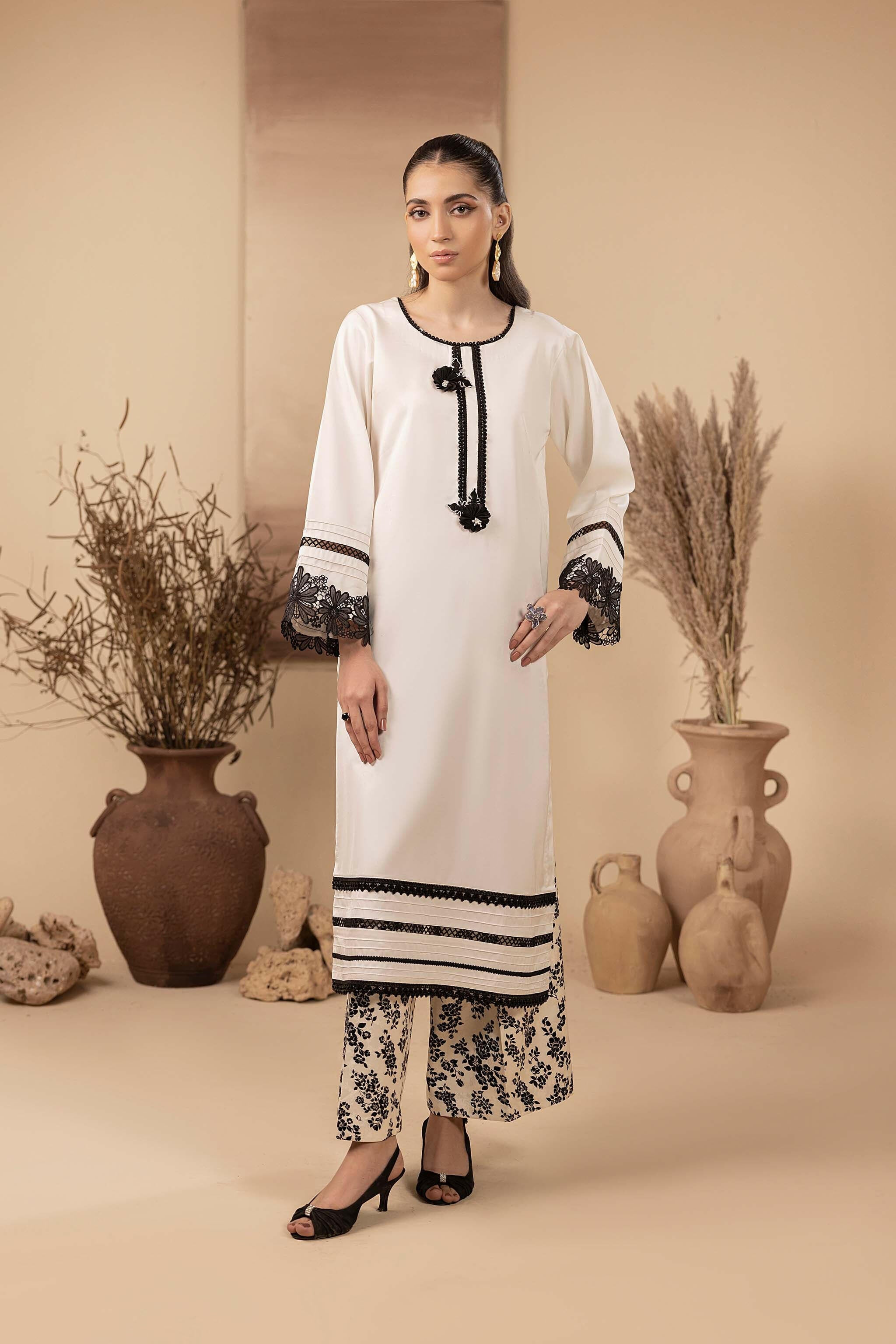 White silk long shirt features embroidered sleeves, an embellished daman, and 3D motifs at the neckline. With flared pants.