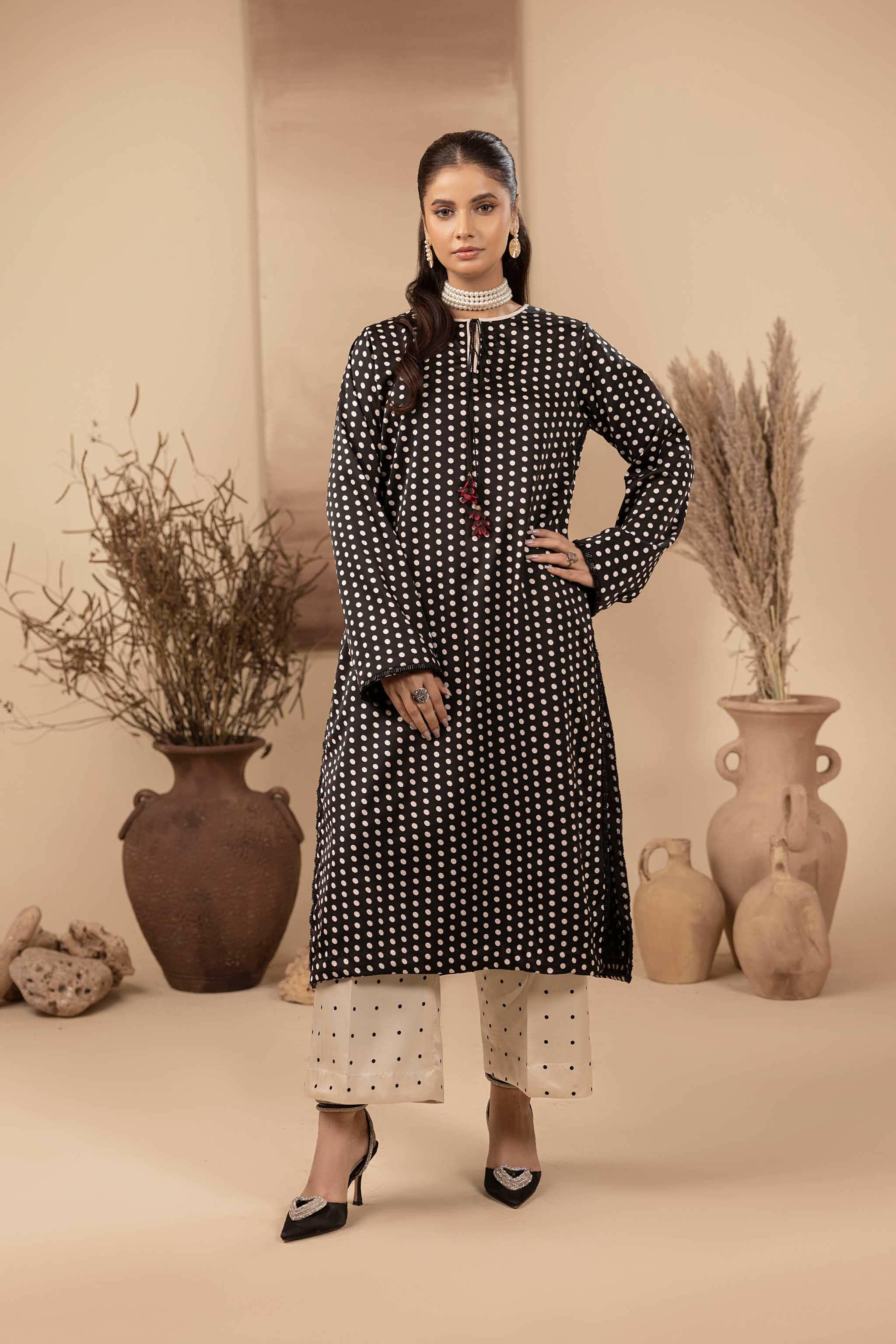 Black polka dot printed shirt in silk. It has embellished side slits and a tassel on the neckline. It is paired up with a white flared lower with black polka dots.